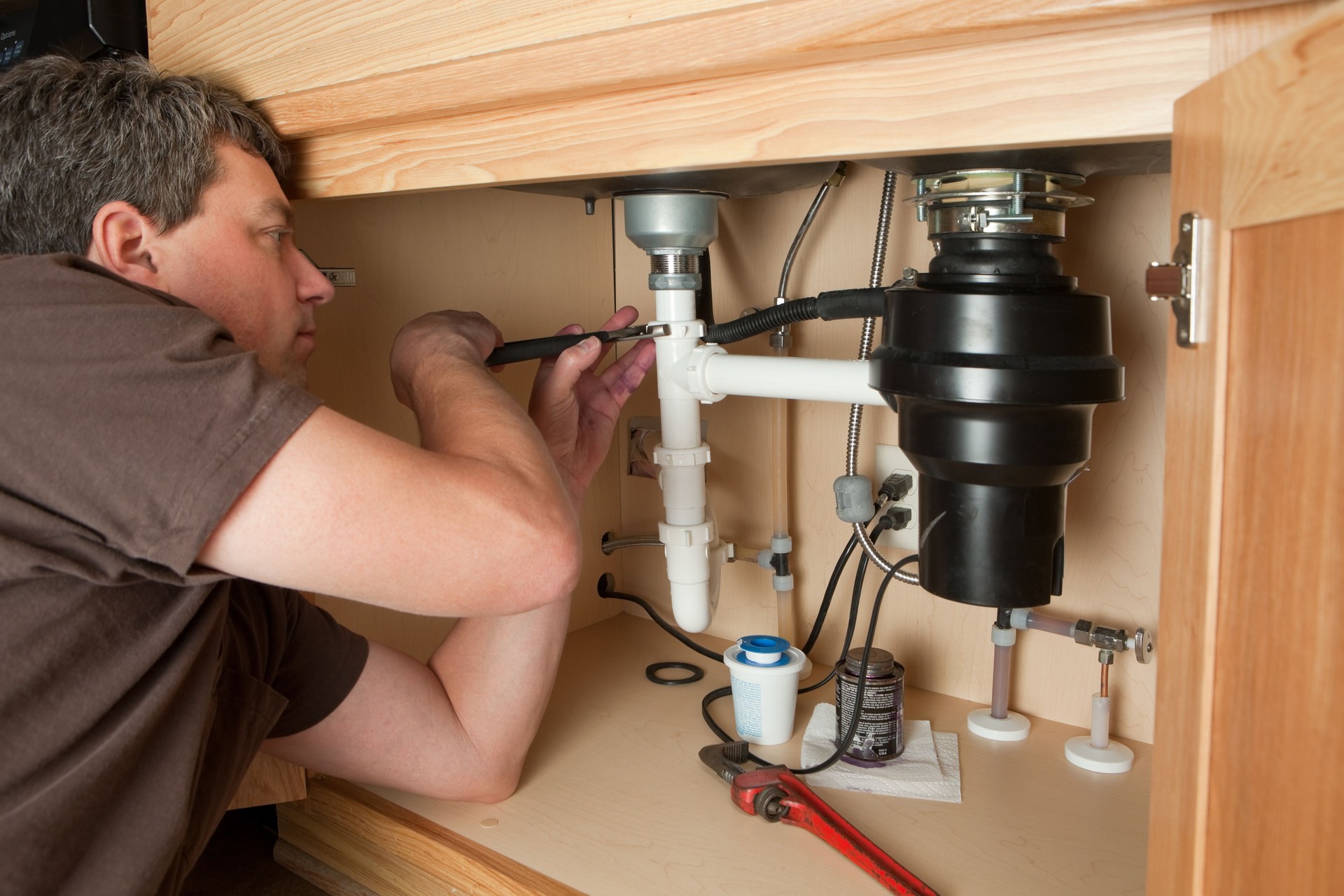 Plumber Using Adjustable Pliers on Sink Drain